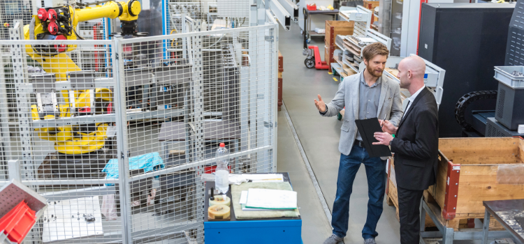 Två personer i samtal framför en industrirobot