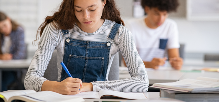 Flicka i klassrum skriver
