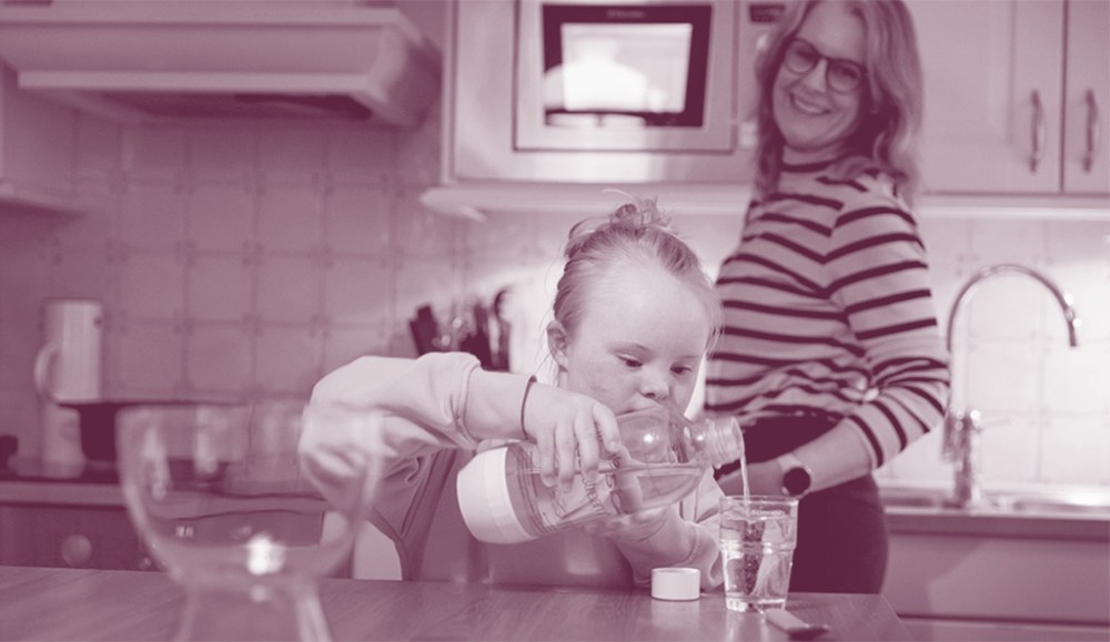 Mamma tittar på när dotter häller mjölk i glas