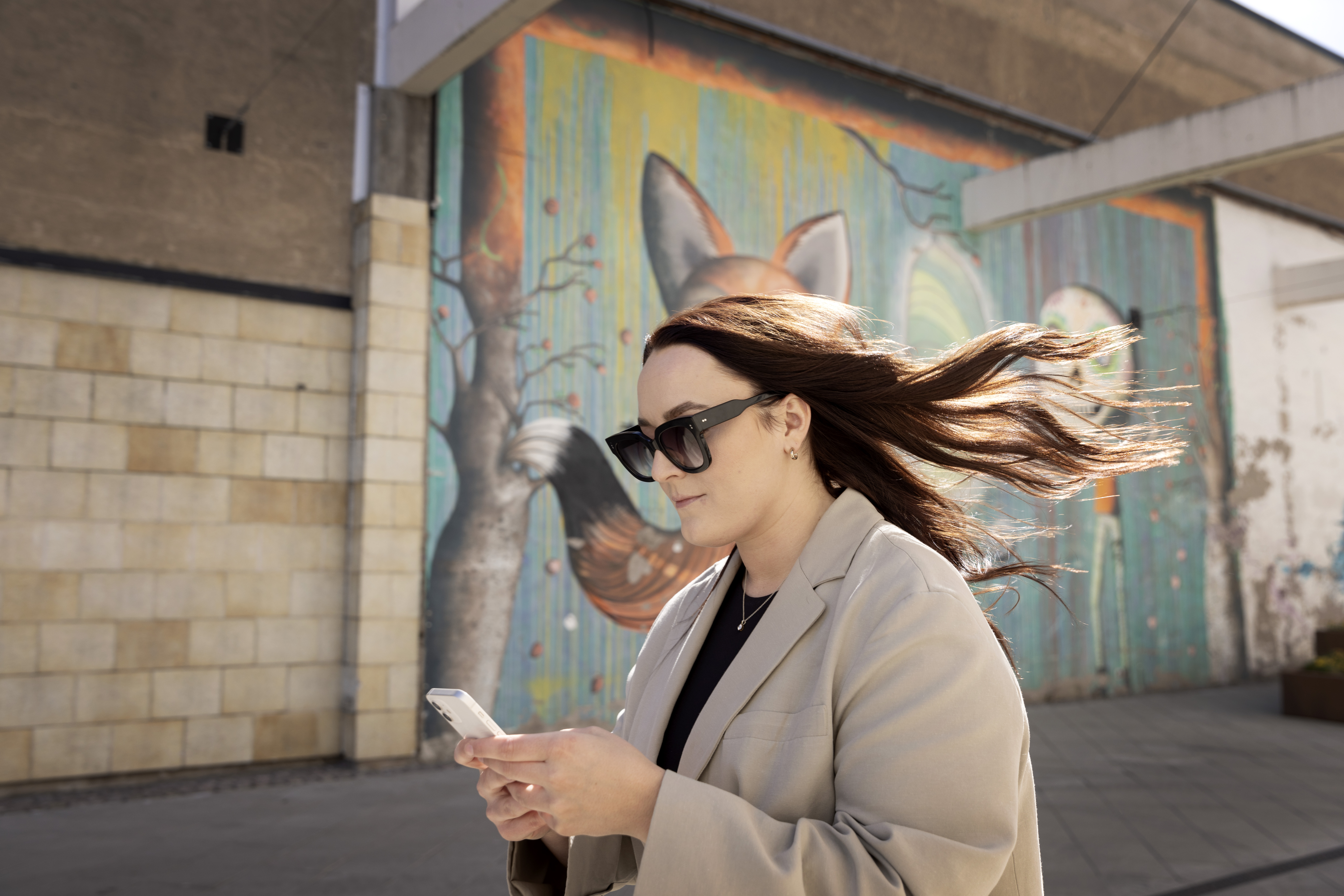 Kvinna går och tittar i mobiltelefon