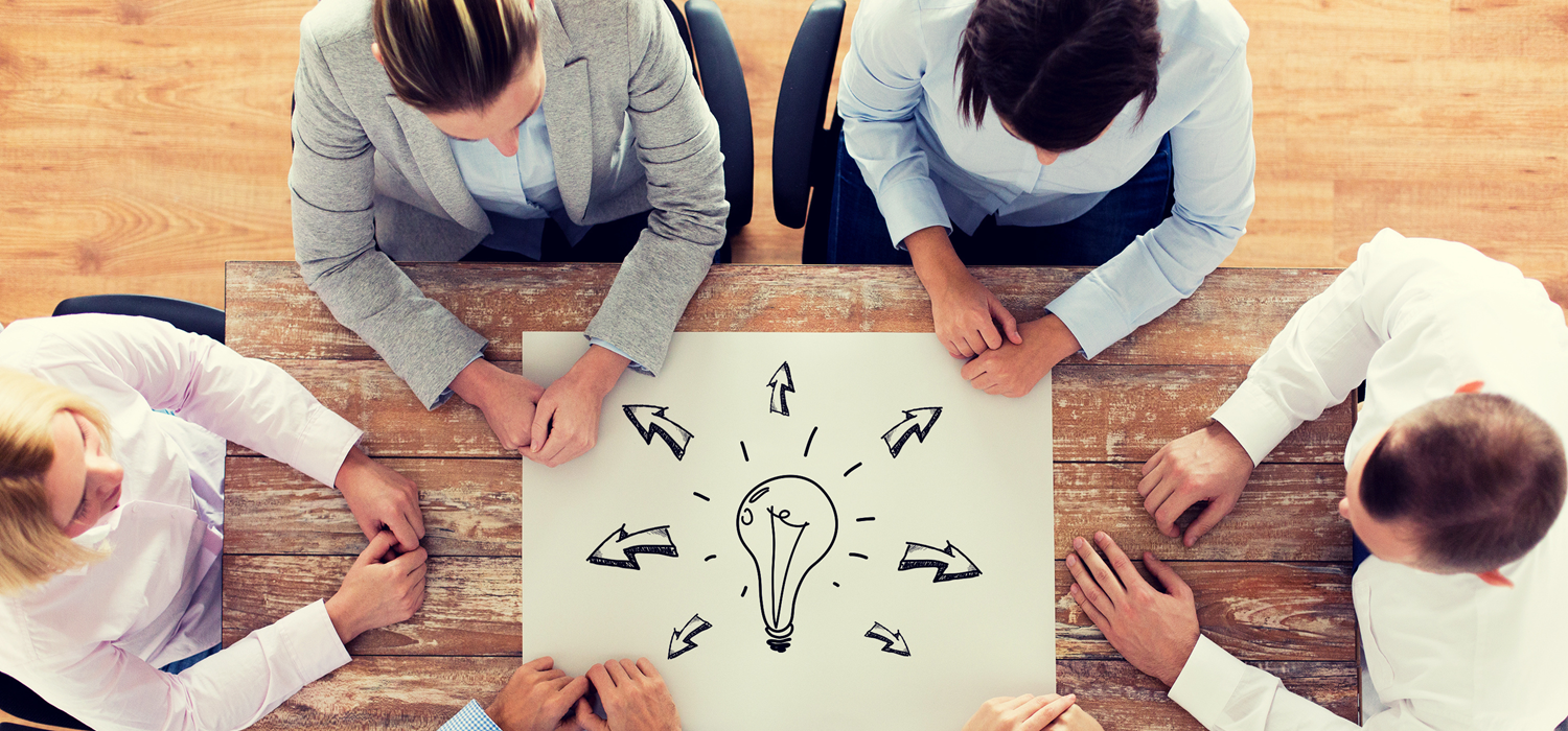 Personer kring ett bord med en teckning av glödlampa och pilar